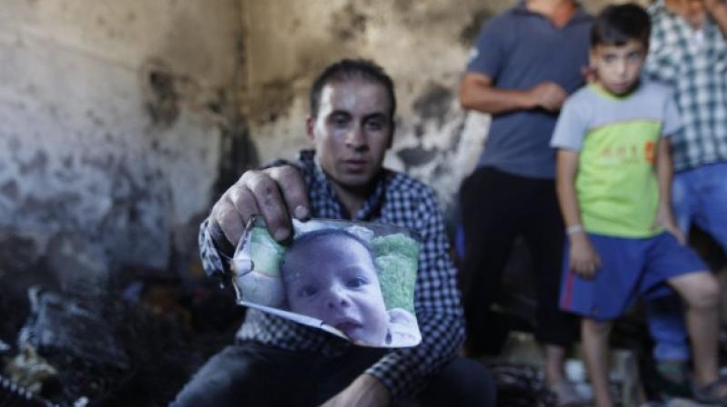 A relative holds up a photo of a one-and-a-half year old boy, Ali Dawabsha, in the family house torched in a suspected attack by Jewish terrorists in Duma village near the West Bank city of Nablus. (Photo: AP)