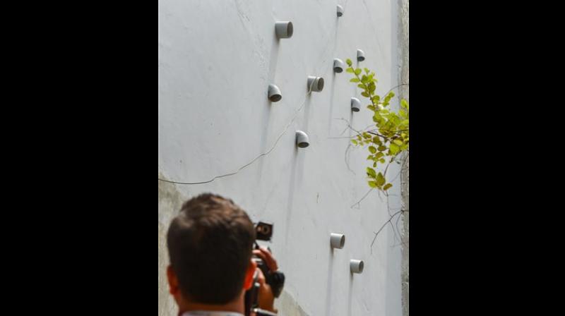 A photographer takes a picture of the 11 pipes protruding out of the house where 11 members of the same allegedly committed suicide, at Burari, in New Delhi. (Photo: PTI)