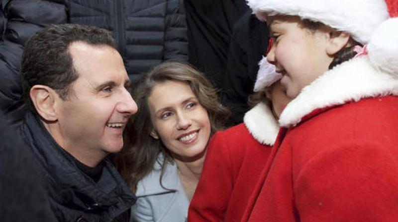 In this photo released on the official Facebook page of the Syrian Presidency, Syrian President Bashar Assad, left, and his wife Asma, center, shake hands with a christian orphan during their visit to Sednaya Convent. (Photo: AP)