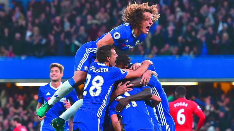 Chelseas Brazilian defender David Luiz (top) jumps onto the huddle to join the celebrations after midfielder NGolo Kante scored Chelseas fourth goal against Manchester United in an English Premier League match at Stamford Bridge in London on Sunday. Chelsea won 4-0 (Photo: AFP)