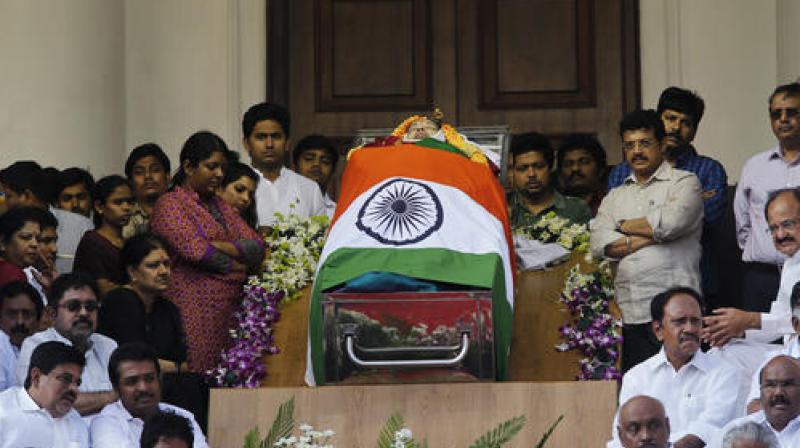 Politicians and friends surround the body of Jayalalithaa, who was dressed in green for her final journey. (Photo: PTI)