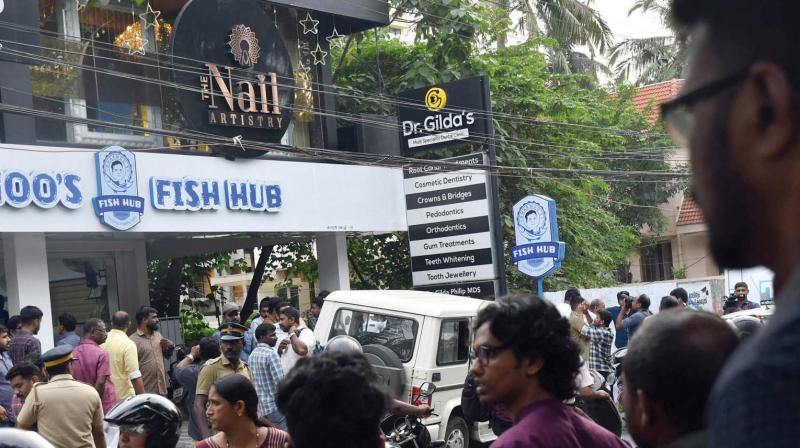 People gather outside the beauty parlour near Panampilly Nagar where two motorcycle-borne unidentified persons fired a couple of shots on Saturday