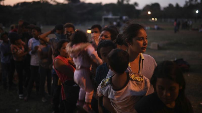Central American migrant women and children stand in line for food during the annual Migrant Stations of the Cross caravan as the group sets up camp at a sports center in Matias Romero, Oaxaca state, Mexico. (Photo: AP)