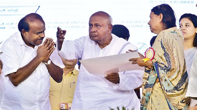 Chief Minister H.D. Kumaraswamy and former PM Deve Gowda at the distribution of debt-free certificates among farmers, in Hassan on Monday.