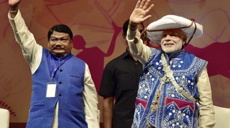 Prime Minister Narendra Modi, in a tribal attire, along with Union Minister for Tribal Affairs, Jual Oram waves at gathering at the inauguration of the National Tribal Carnival-2016 in New Delhi on Tuesday. (Photo: PTI)