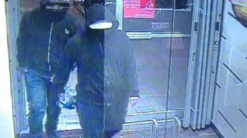 Police posted a photograph on Twitter showing two people with dark zip-up hoodies walking into an establishment with one of them appearing to be carrying an object. (Photo | Peel Regional Police Twitter)