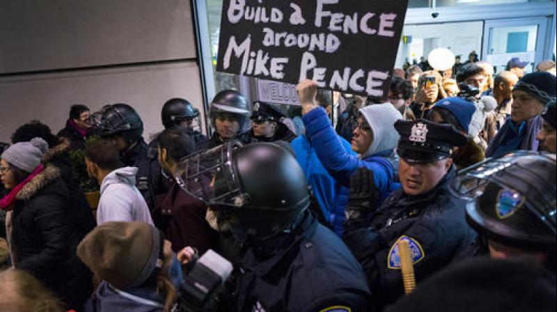 Protesters are surrounded by police officers and travelers as they pass through an exit of Terminal 4 at John F. Kennedy International Airport in New York. (Photo: AP)