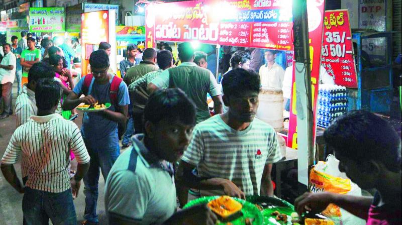 Youngsters relishing biryani, dosas and others at a night food court near the Indira Gandhi Municipal Stadium in Vijayawada on Tuesday. (Photo: DC)