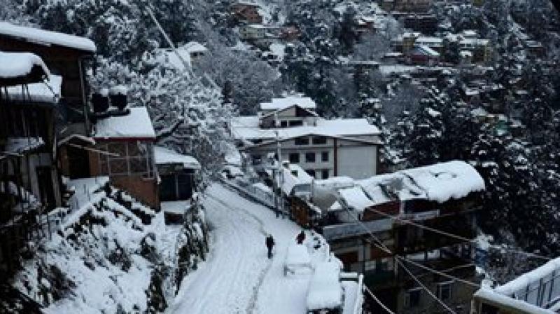 People walk on snow-covered road after a heavy snowfall in Shimla on Saturday morning. (Photo: PTI)