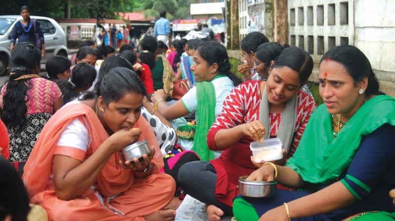 Members of United Nurses Association who have been on an indefinite strike since Monday demanding better wages having lunch on the footpath in front of Thrissur collectorate on Tuesday. (Photo: ANUP K. VENU)