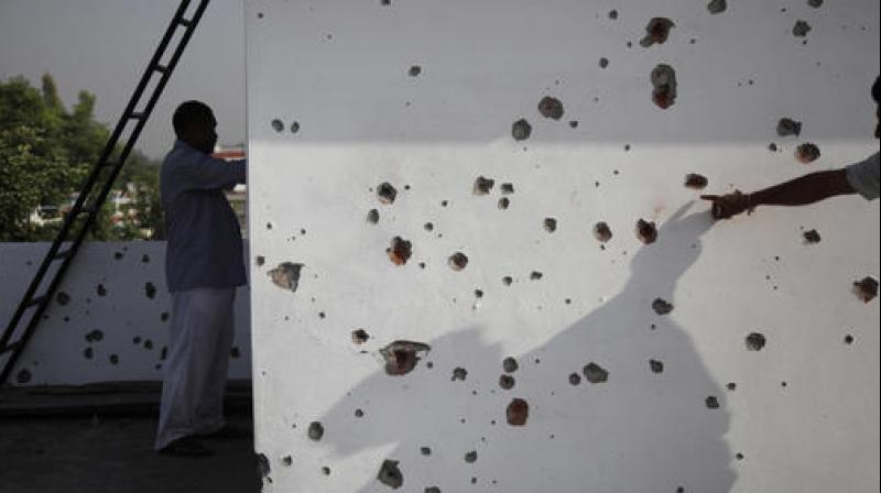 A villager points to marks made on a wall allegedly from firing from the Pakistan side of the border, at a residential area near the India Pakistan border in Ranbir Singh Pura, about 40 kilometers from Jammu. (Photo: PTI)