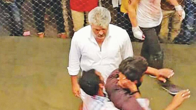 The pictures show Ajith wearing a white veshti and shirt, with his usual salt-and-pepper hair and a thick moustache, observing stuntmen perform the fight before the actual shot.