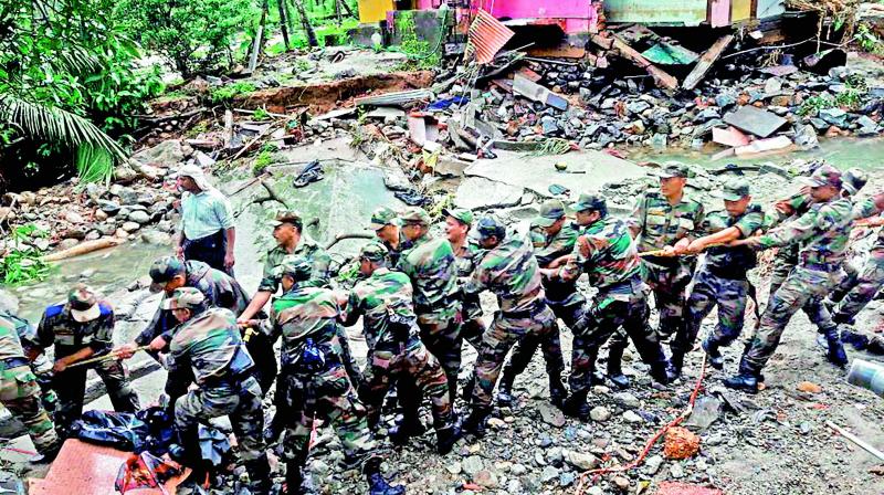 Soldiers clear the debris off a road in a flooded affected area at Wayanad.