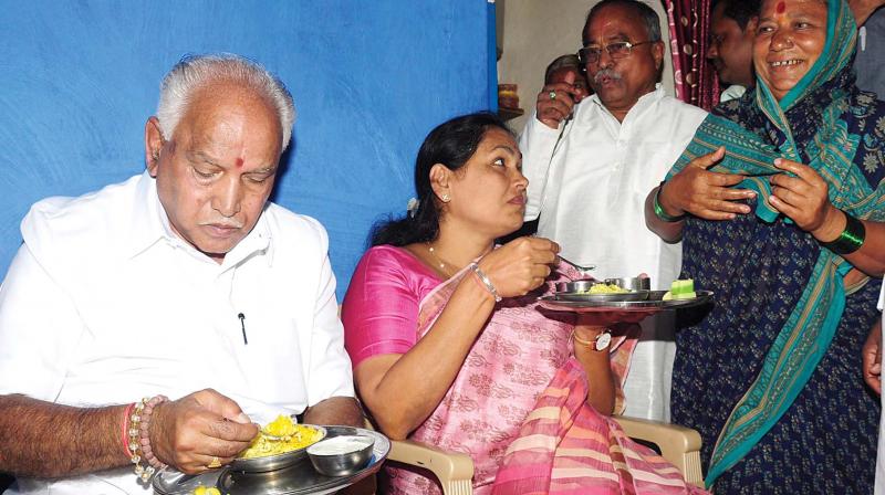 State BJP president B.S. Yeddyurappa and senior party leader Shobha Karandlaje have breakfast at a Dalits house in Bagalkot on Monday. (Photo: KPN)