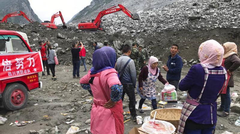 Women watch as earthmoving equipment digs at the site of a landslide in Xinmo village in Maoxian County in southwestern Chinas Sichuan Province, Sunday. (Photo: AP)