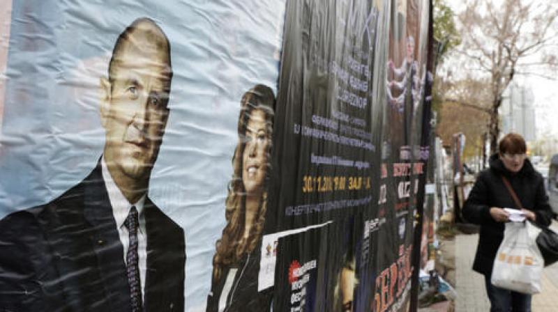 A woman passes near pre-election posters of Bulgarias Socialist party presidential candidate Rumen Radev and vice-president Iliana Yotova, right, in Sofia. (Photo: AP)