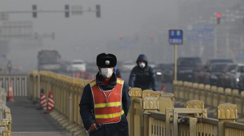 A traffic warden wearing a protection mask walks on a street near Tiananmen Square in Beijing as the capital of China is blanketed by heavy smog on January 4. (Photo: AP)