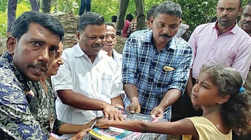 The members distribute study materials to a child. Devikulam MLA S. Rajendran is also seen.