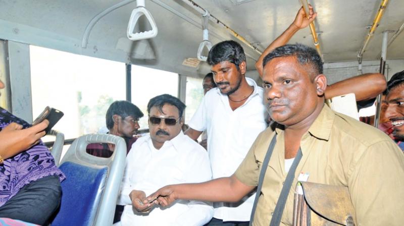 A woman co-passenger clicks a photo on her mobile and a man in the bus is unable to suppress his glee as DMDK chief Vijayakanth buys his bus ticket travelling by public transport from Saidapet to Pallavaram to know first-hand the conditions of the government buses and the travails of the passengers. Vijayakanth was on his way to participate in his party agitation against the bus fare hike. In a statement later, he said he found the seats in the bus in bad condition and the commuters told him they found the fare hike to be huge burden on their budget (Photo: DC)