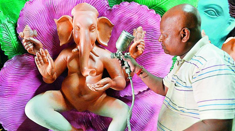 An artist spray paints eco-friendly figures Ganesh at a workshop in Hyderabad.(Photo: PTI)
