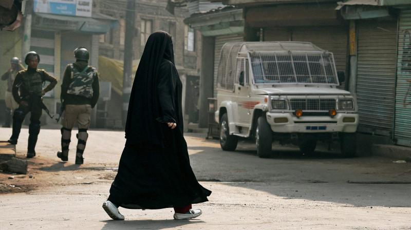 A burqa-clad woman walks past CRPF jawans in Srinagar. (Photo: PTI)