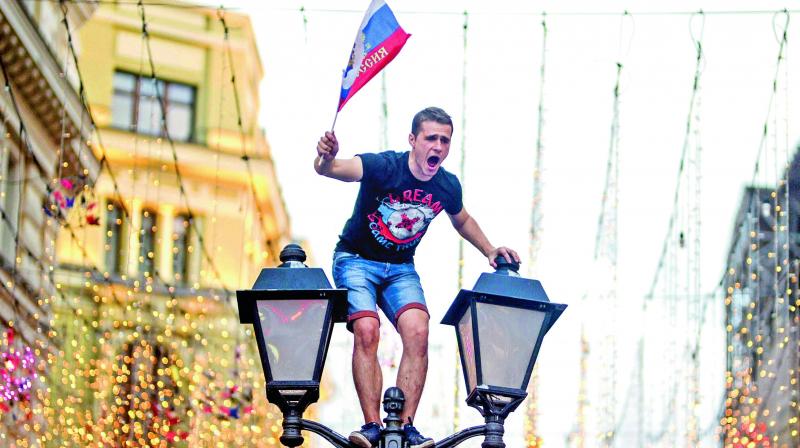 A Russian fan  celebrates on a  lamp post in central Moscow. (Photo: AFP)