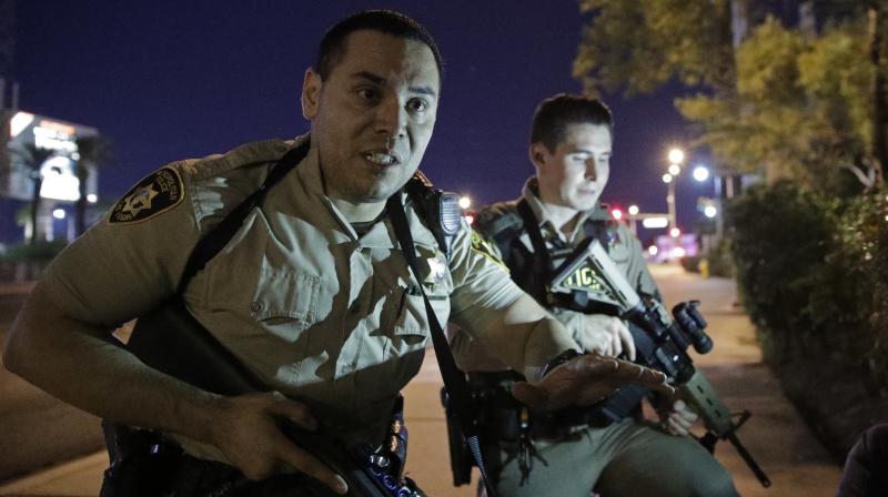 Police officers advise people to take cover near the scene of a shooting near the Mandalay Bay resort and casino on the Las Vegas Strip, Sunday
