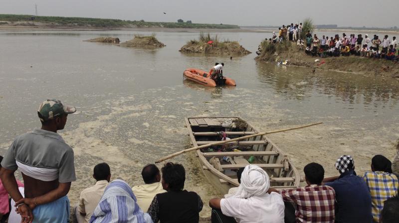 Rescuers search in the Yamuna River as villagers gather after a country boat, seen in foreground, capsized near Baghpat town in Uttar Pradesh on Thursday. (Photo: AP)