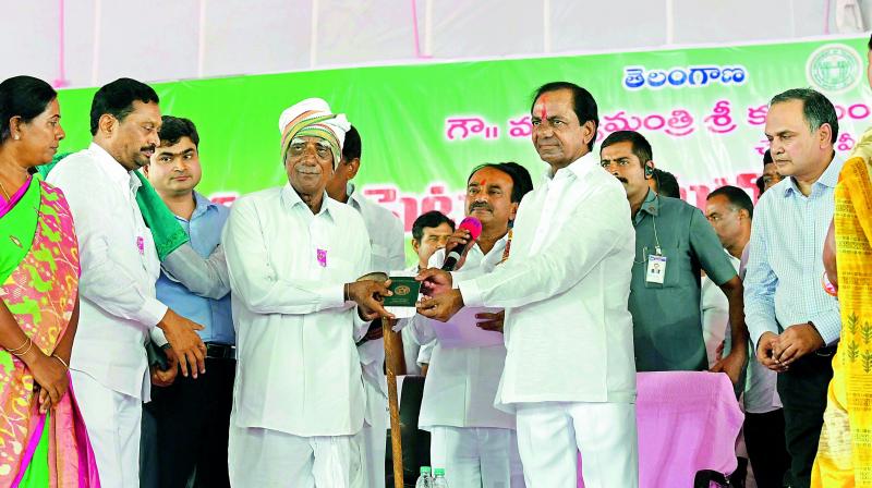 Chief Minister K. Chandrasekhar Rao hands over Rs 4,000 per acre cheque and e-pattadar passbook to a farmer during the launch of Rythu Bandhu scheme in Karimnagar on Thursday. Finance minister Etela Rajender is also seen. (Photo: DC)