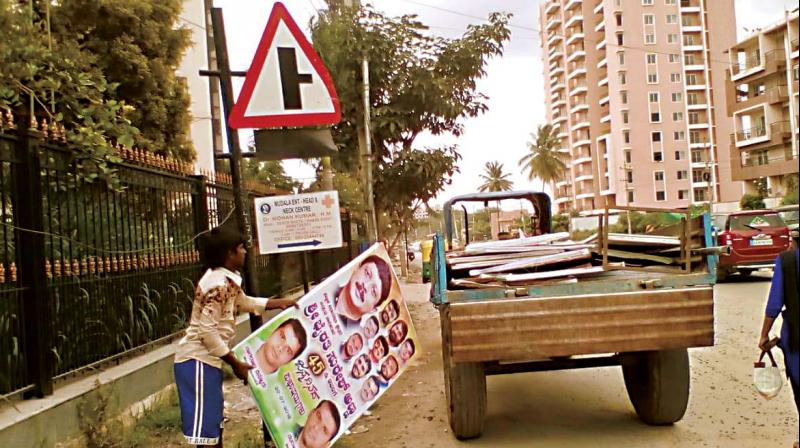 A BBMP worker removes flexes at a traffic junction, in Bengaluru