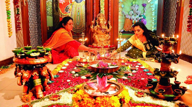 Women lighting up clay diyas and decorating floral rangolis for Diwali festivities