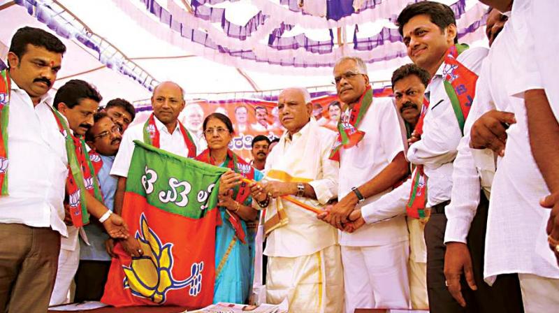 State BJP chief B.S. Yeddyurappa handing over the party flag to former minister H. Nagappas wife Parimala Nagappa who joined the party at Hanur on Thursday. (Photo: DC)