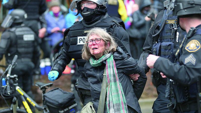 A woman is detained during a protest as thousands turned out across the US to challenge Donald Trump in a Presidents Day protest dubbed Not My Presidents Day. (Photo: AP)