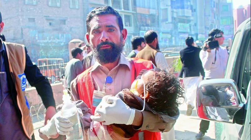 A Pakistani volunteer carries an injured child to a hospital in Peshawar, Pakistan, on Tuesday.(Photo: AP)