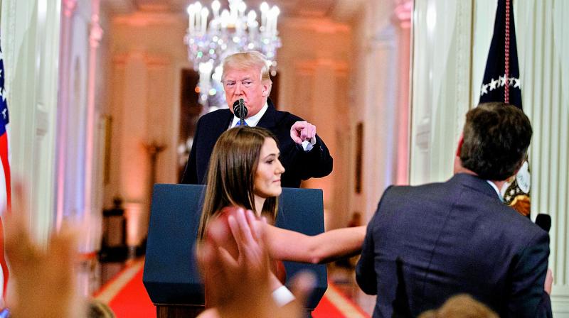 President Donald Trump watches as a White House aide reaches to take away a microphone from CNN journalist Jim Acosta during a news conference. (Photo: AP)
