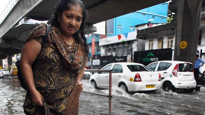 A woman wades through the water logged M G Road after heavy rains in Kochi. (Photo: PTI)