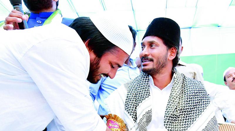 A Muslim youth tying imam-e-zamin to Y.S. Jagan Mohan Reddy at Kalluru in Chittoor on Saturday. (Photo: DC)