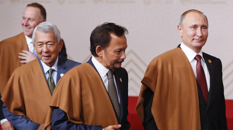 Russias President Vladimir Putin, right, walks with Bruneis Sultan Hassanal Bolkiah, center, after posing for an official photo at the Asia-Pacific Economic Cooperation (APEC), Peru, on Sunday. (Photo: AP)