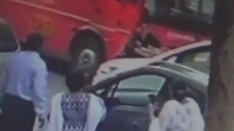 The video grab of the incident showing the man on the bonnet of the car. (Photo: ANI/Twitter)