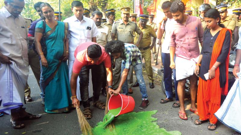 ABVP activists  symbolically clean up the front gate of Maharajas College, Kochi, where some SFI activists had put the principals chair to fire. 	(Photo: DC)