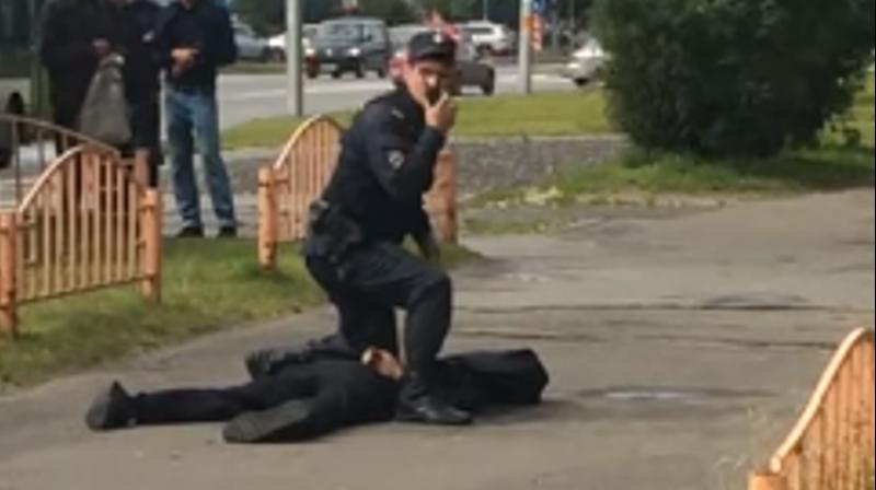 A police official with the killed assailant in Russias Surgut on Saturday. (Photo: Screengrab)