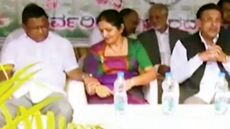 A still of T.P. Ramesh attempting to hold MLC Veena Achaiahs hand at an Independence Day event (inset) T.P. Ramesh, who handed over his resignation earlier this week