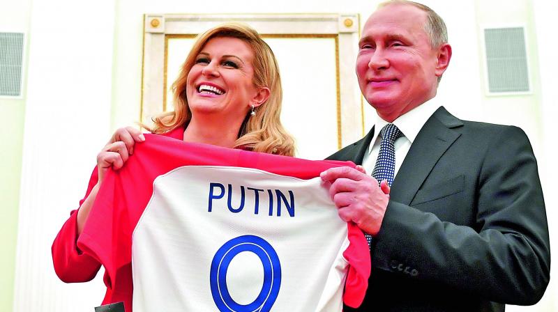 Croatian President Kolinda Grabar Kitarovic (left) presents a T-shirt to Russian President Vladimir Putin. (Photo: AP)