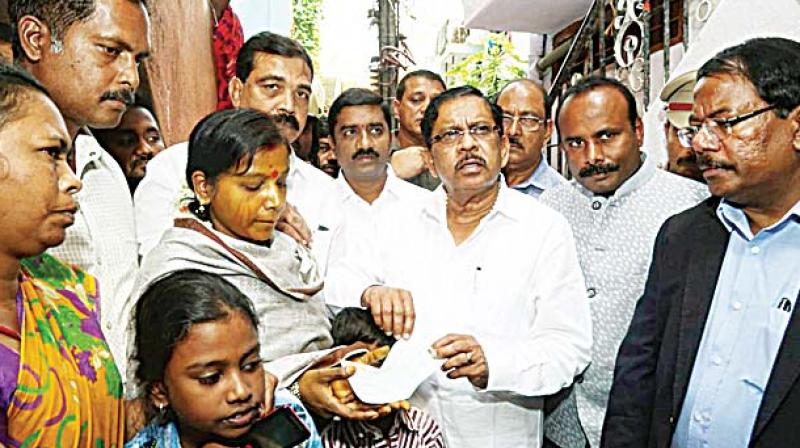 Deputy Chief Minister Dr G. Parameshwar presents a cheque to the wife of pourakarmika T. Subramani, who committed suicide recently, at their house in Bengaluru on Sunday. Mayor Sampath Raj (second from right) and BBMP Commissioner Manjunath Prasad (extreme right) are also seen	 (Photo: KPN)