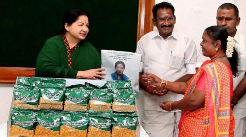 Tamil Nadu Chief Minister J Jayalalithaa gives a dal packet to a beneficiary after introducing a scheme of providing dals at cheap rates in Chennai. (Photo: PTI/File)