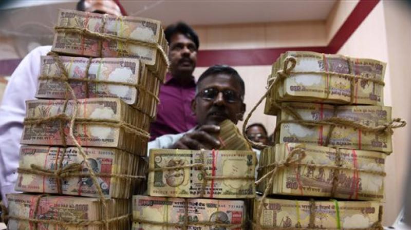A Bank Employee counting the bundles of the received currency of old 1000 & 500 notes at cash counter. (Photo: PTI)
