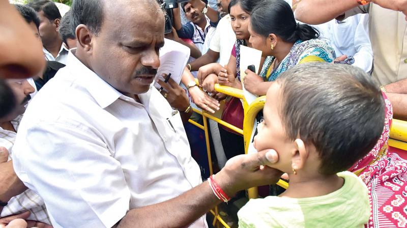 Chief Minister H.D. Kumaraswamy with a child at the Janata Darshan programme in Bengaluru on Friday  (Image: KPN)