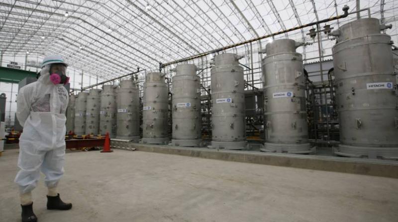 A Tepco official wearing radioactive protective gear stands in front of Advanced Liquid Processing Systems during a media tour at the Fukushima No. 1 nuclear power plant in November 2014. Photo:AP