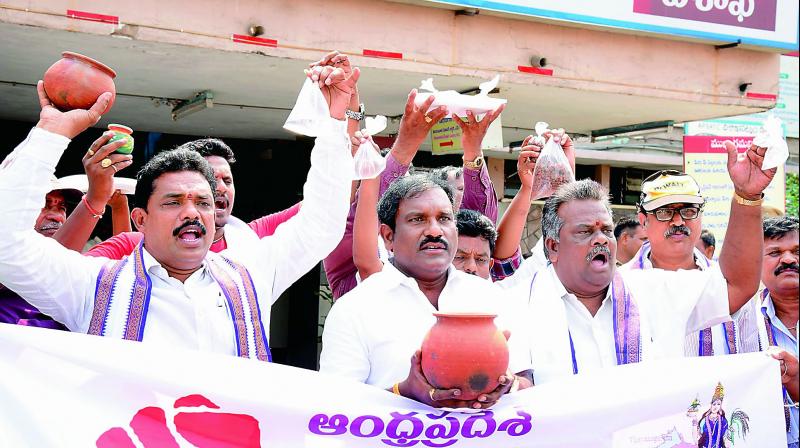 Activists display pots of mud and water as a part of a protest to highlight what Modi has given to AP, in Visakhapatnam on Wednesday. (Photo: DC)