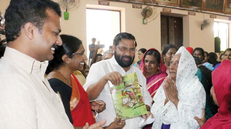 Devaswom minister Kadakampally Surendran hands over the literacy textbook to 70-year-old Abusabeevi during the pravesanolsavam.